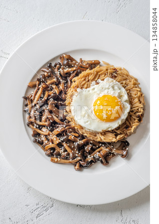 Savory fried rice topped with umami Shimeji mushrooms and golden sunny egg 134858044