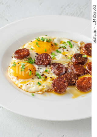 Hearty fried eggs served with caramelized chorizo slices and fresh scallion garnish 134858052