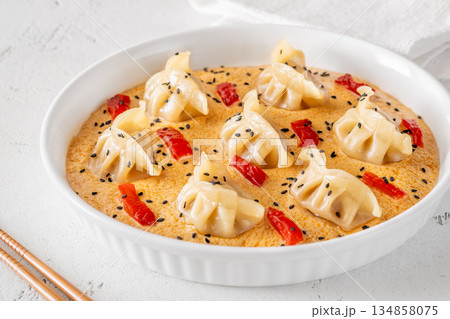 Steamed gyoza dumplings in creamy Tom Yum sauce with sesame garnish 134858075
