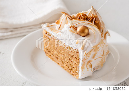 Slice of Medovik honey cake with toasted meringue and golden garnish 134858082
