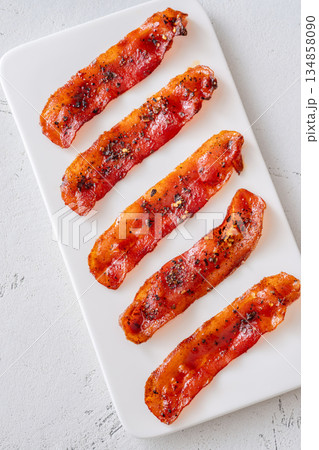 Billionaire bacon strips glazed with pepper and chili flakes on minimalist plate 134858090