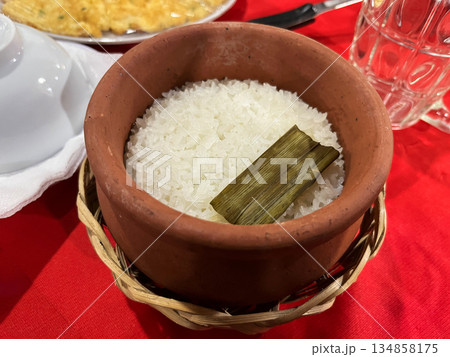 Traditional Vietnamese cooked white rice in a clay pot, served on a red table 134858175