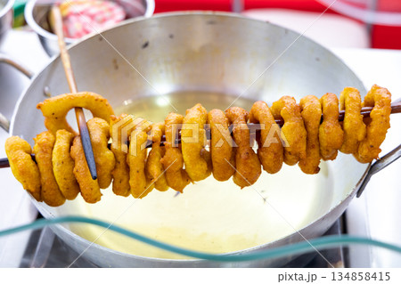 A long stick of picarones is being cooked in a pan 134858415