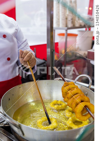 A woman is cooking picarones in a pan A woman is cooking picarones in a pan 134858426