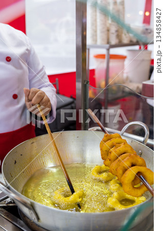 A woman is cooking picarones in a pan A woman is cooking picarones in a pan 134858427