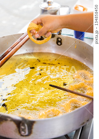 A woman is cooking picarones in a pan. A woman is cooking picarones in a pan. 134858450