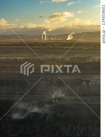 Aerial view of an active coal mining site showcases heavy machinery and smoke billowing into the air 134858681