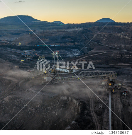 Aerial view of an active coal mining site showcases heavy machinery and smoke billowing into the air Aerial view of an active coal mining site showcases heavy machinery and smoke billowing into the air 134858687