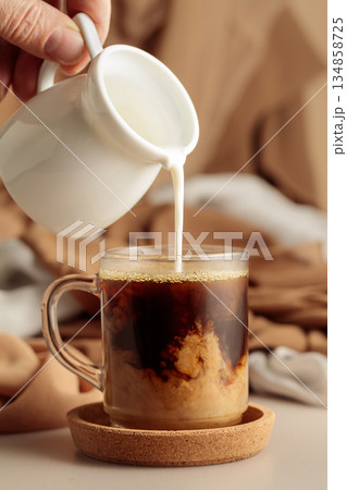 Pouring cream in black coffee. 134858725