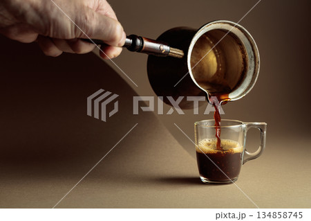 Black coffee is poured into a glass cup. Black coffee is poured into a glass cup. 134858745