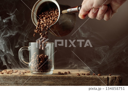 Roasted coffee beans is poured in a clear glass mug. 134858751