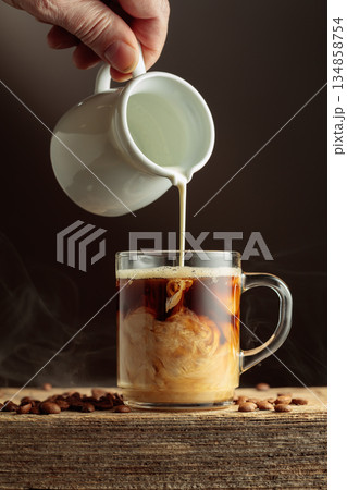 Coffee in a clear glass mug with cream being poured. Coffee in a clear glass mug with cream being poured. 134858754