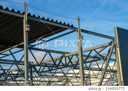 Steel roof and sandwich panel wall assembly on modern industrial warehouse construction site Steel roof and sandwich panel wall assembly on modern industrial warehouse construction site 134858775
