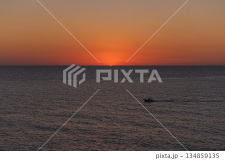 A boat cruising on calm sea at dawn or dusk. 134859135