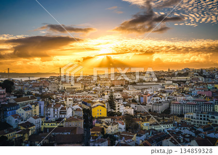 Golden hour cityscape over Lisbon, Portugal, historic center, Tagus river with dramatic clouds, Ponte 25 de Abril or April 25th bridge silhouette, sunlight, colorful tiled rooftops. Beautiful sunset Golden hour cityscape over Lisbon, Portugal, historic center, Tagus river with dramatic clouds, Ponte 25 de Abril or April 25th bridge silhouette, sunlight, colorful tiled rooftops. Beautiful sunset 134859328