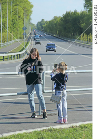 Little girls take pictures of each other near the highway. Happy children 134860381
