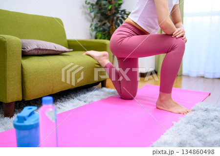 ブルガリアンスクワット　ヨガウェアを着て室内で下半身を鍛える若い女性　ヒップアップ　きつい　休憩 134860498