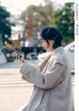 屋外で座ってスマートフォンを見る30代女性のライフスタイル 134860734