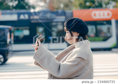 屋外で座ってスマートフォンを見る30代女性のライフスタイル 屋外で座ってスマートフォンを見る30代女性のライフスタイル 134860735
