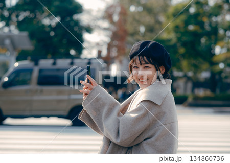 屋外で座ってスマートフォンを見る30代女性のライフスタイル 屋外で座ってスマートフォンを見る30代女性のライフスタイル 134860736