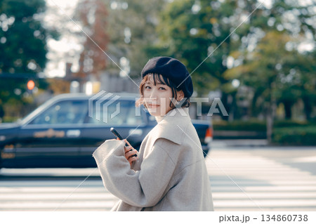 屋外で座ってスマートフォンを見る30代女性のライフスタイル 134860738