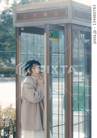公衆電話で通話する30代女性のライフスタイルシーン 公衆電話で通話する30代女性のライフスタイルシーン 134860763