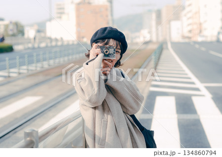 カメラを構えて笑顔を見せる30代女性のポートレート カメラを構えて笑顔を見せる30代女性のポートレート 134860794
