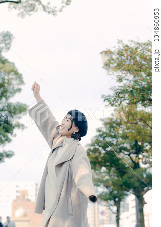 青空の下でリラックスして伸びをする30代女性のポートレート 134860953