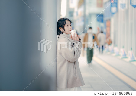 バス停でコーヒーを飲みながら待つ30代女性のポートレート バス停でコーヒーを飲みながら待つ30代女性のポートレート 134860963