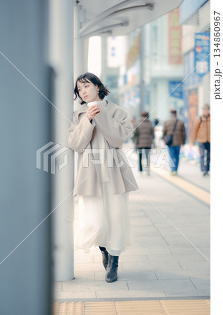 バス停でコーヒーを飲みながら待つ30代女性のポートレート バス停でコーヒーを飲みながら待つ30代女性のポートレート 134860967
