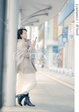 バス停でコーヒーを飲みながら待つ30代女性のポートレート 134860972