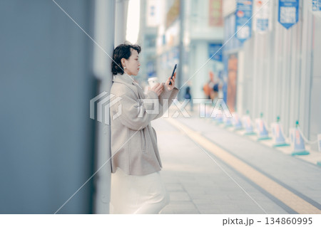 バス停でスマートフォンを操作しながら待つ30代女性 134860995