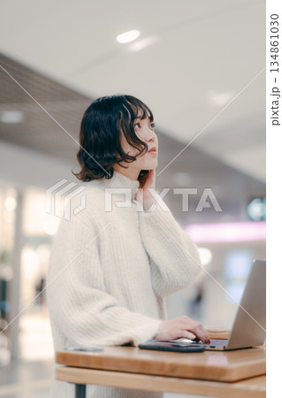 街中でノートパソコンを操作する30代女性 街中でノートパソコンを操作する30代女性 134861030