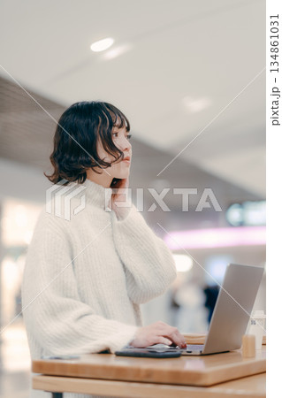 街中でノートパソコンを操作する30代女性 134861031