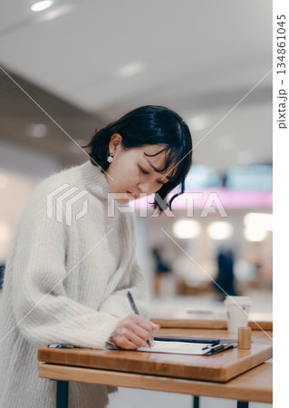 街中でメモを書きながら作業する30代女性 街中でメモを書きながら作業する30代女性 134861045