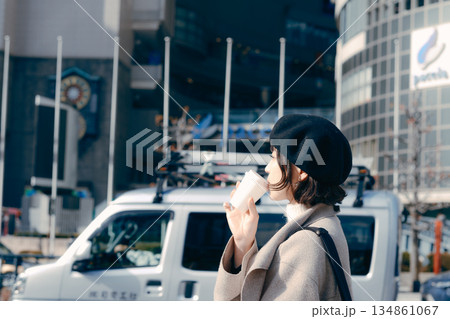 街中でコーヒーを持ち歩きながら過ごす30代女性 134861067