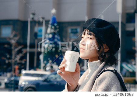 街中でコーヒーを持ち歩きながら過ごす30代女性 134861068