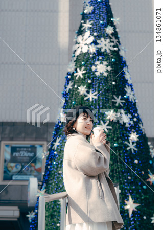イルミネーションの前でコーヒーを飲みながら過ごす女性 イルミネーションの前でコーヒーを飲みながら過ごす女性 134861071