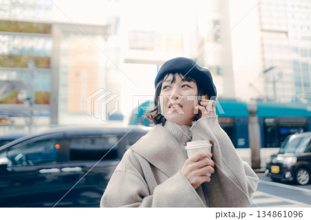 街中でコーヒーを持ちながら歩く女性 134861096