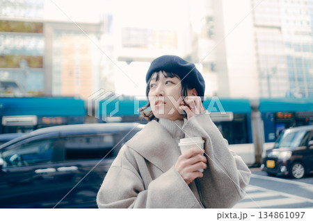 街中でコーヒーを持ちながら歩く女性 134861097