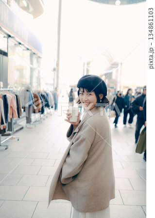 街中でコーヒーを持ちながら歩く女性 街中でコーヒーを持ちながら歩く女性 134861103