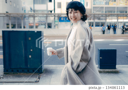 街中でコーヒーを持ちながら歩く女性 134861113