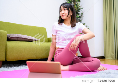 脚のストレッチ タブレットでYouTube動画を見ながら自宅で柔軟、ヨガをする若い女性 ヨガウェア 脚のストレッチ タブレットでYouTube動画を見ながら自宅で柔軟、ヨガをする若い女性 ヨガウェア 134861556