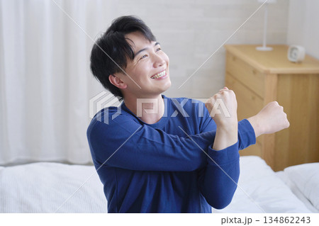 ベッドに座って腕のストレッチをする20代男性 ベッドに座って腕のストレッチをする20代男性 134862243