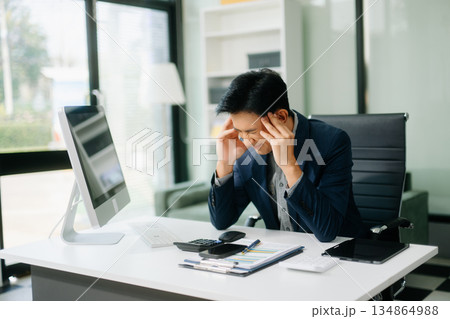 Frustrated young businessman working on a laptop computer sitting at his working place 134864988