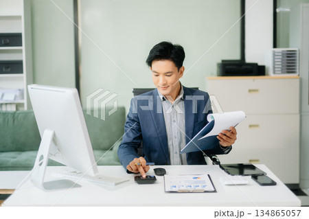 Asian businessman working with working notepad, tablet and laptop documents talking on the smartphone, tablet and laptop 134865057