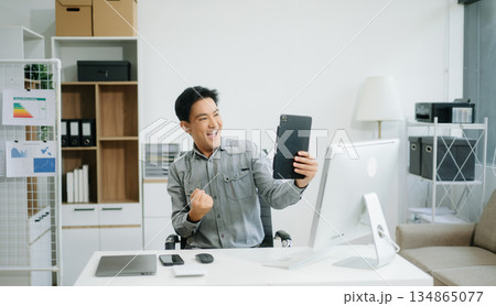 Confident businessman working on finance analysis with a tablet and laptop at office desk. Confident businessman working on finance analysis with a tablet and laptop at office desk. 134865077