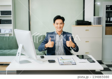Young attractive Asian male office worker business suits smiling at camera Young attractive Asian male office worker business suits smiling at camera 134865080