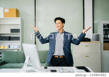Young attractive Asian male office worker business suits smiling at camera Young attractive Asian male office worker business suits smiling at camera 134865083