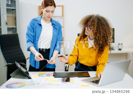 Women designers working on mobile app UX UI with color palettes, wireframes, and sticky notes. Teamwork, prototyping, and layout planning 134865298